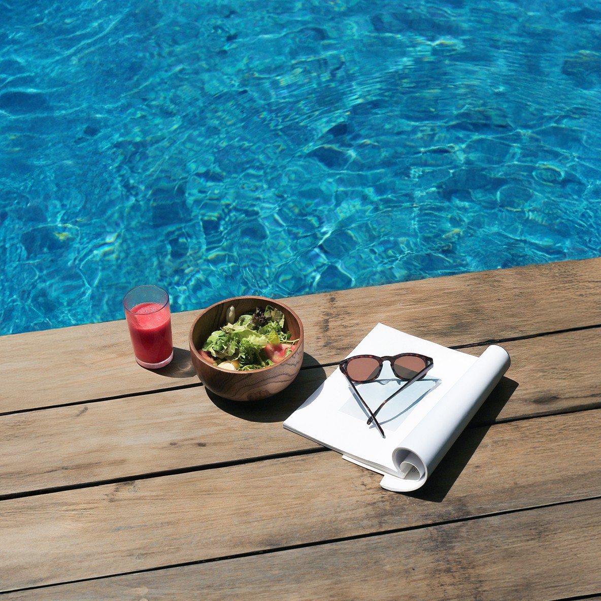 Salad and smoothie on a wooden pool deck